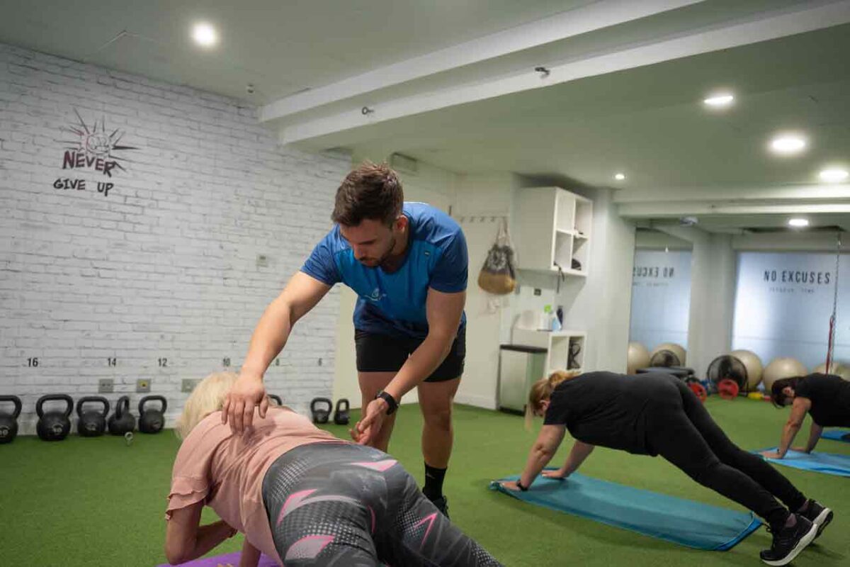 Instructor asiste a mujer mayor en ronda de ejercicios