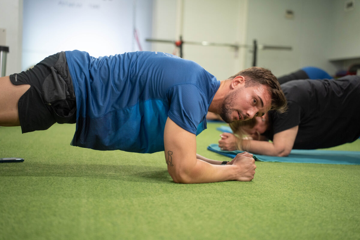 Entrenador dirige sesión de flexiones en una colchoneta de Global Salud